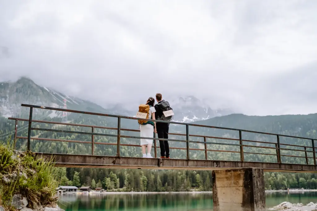 Paar steht auf der Brücke am Eibsee und schaut Richtung Zugspitze
