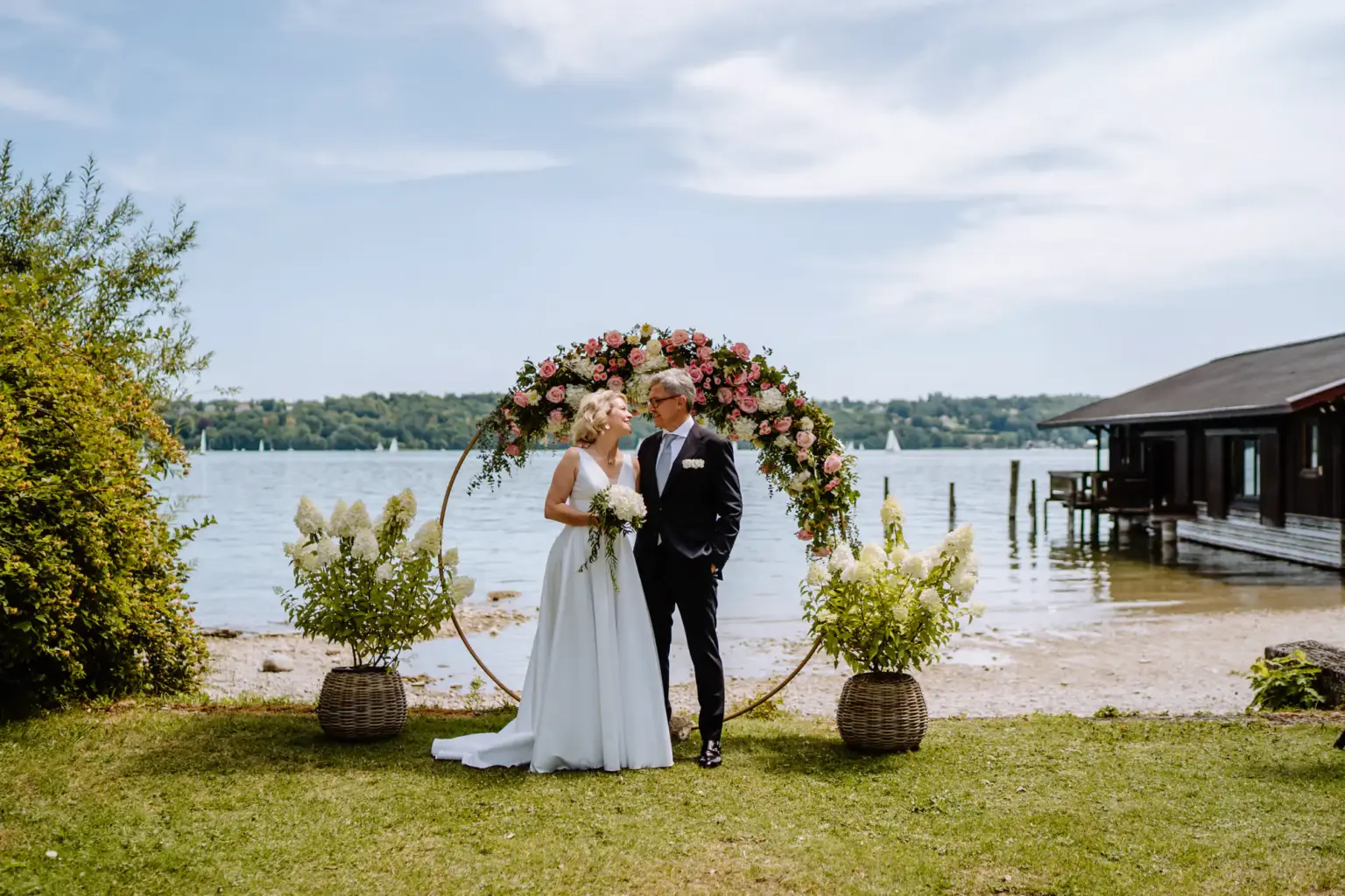Hochzeitspaar vor dem wunderschönen Traubogen direkt am Ufer vom Starnberger See