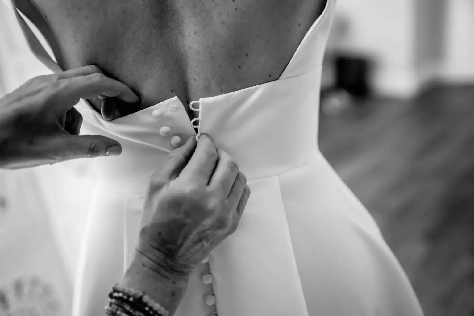 Braut wird von Freundinnen beim Anziehen des Kleides unterstützt