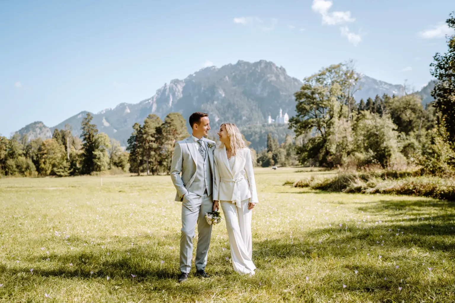 Leises Lächeln zwischen Braut und Bräutigam mit dem Schloß Neuschwanstein im Hintergrund