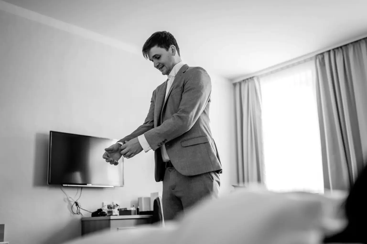 Bräutigam wird von Freunden beim Anziehen des Hochzeitsanzugs unterstützt