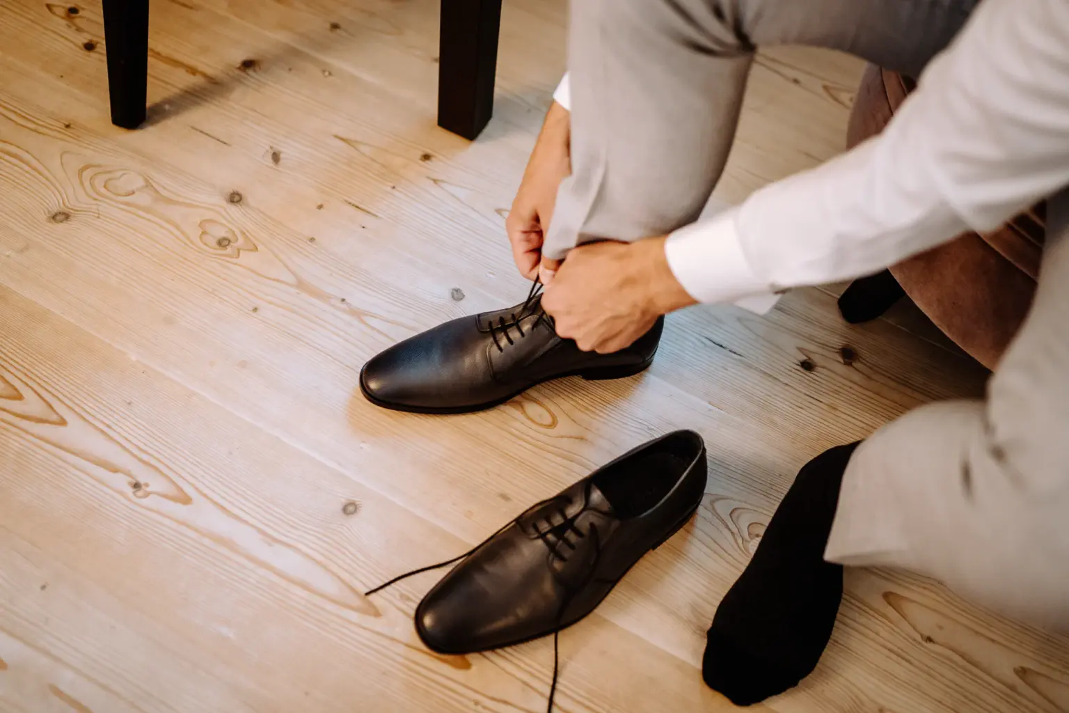Bräutigam bindet sich die Schuhe beim Getting Ready