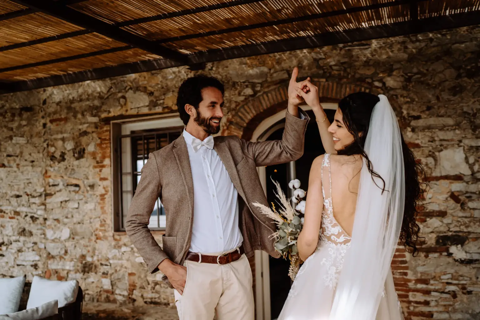 Braut tanzt in der Hand vom Bräutigam auf der Terrasse der Villa in der Toskana