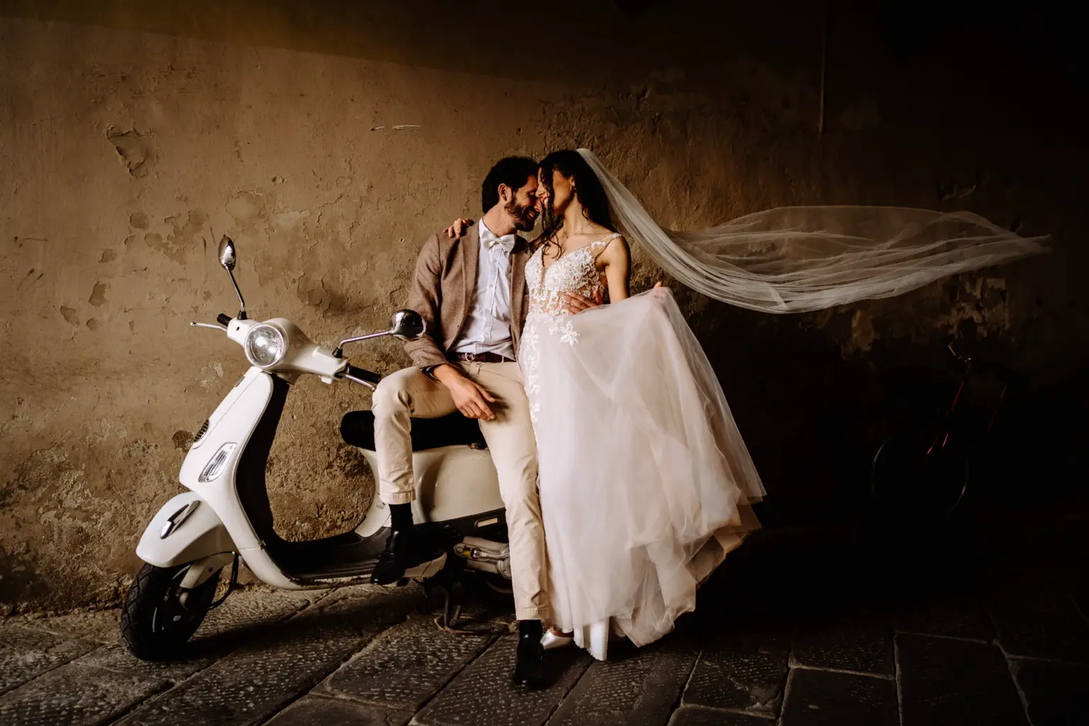 Brautpaar - mit Braut und ihrem wehenden Schleier - sitzt auf einer Vespa
