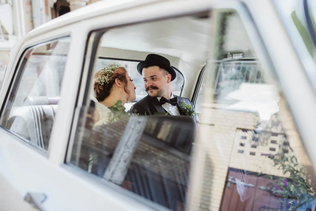 Braut und Bräutigam im alten Alfa Romeo im Hof vom Hochschloß Pähl