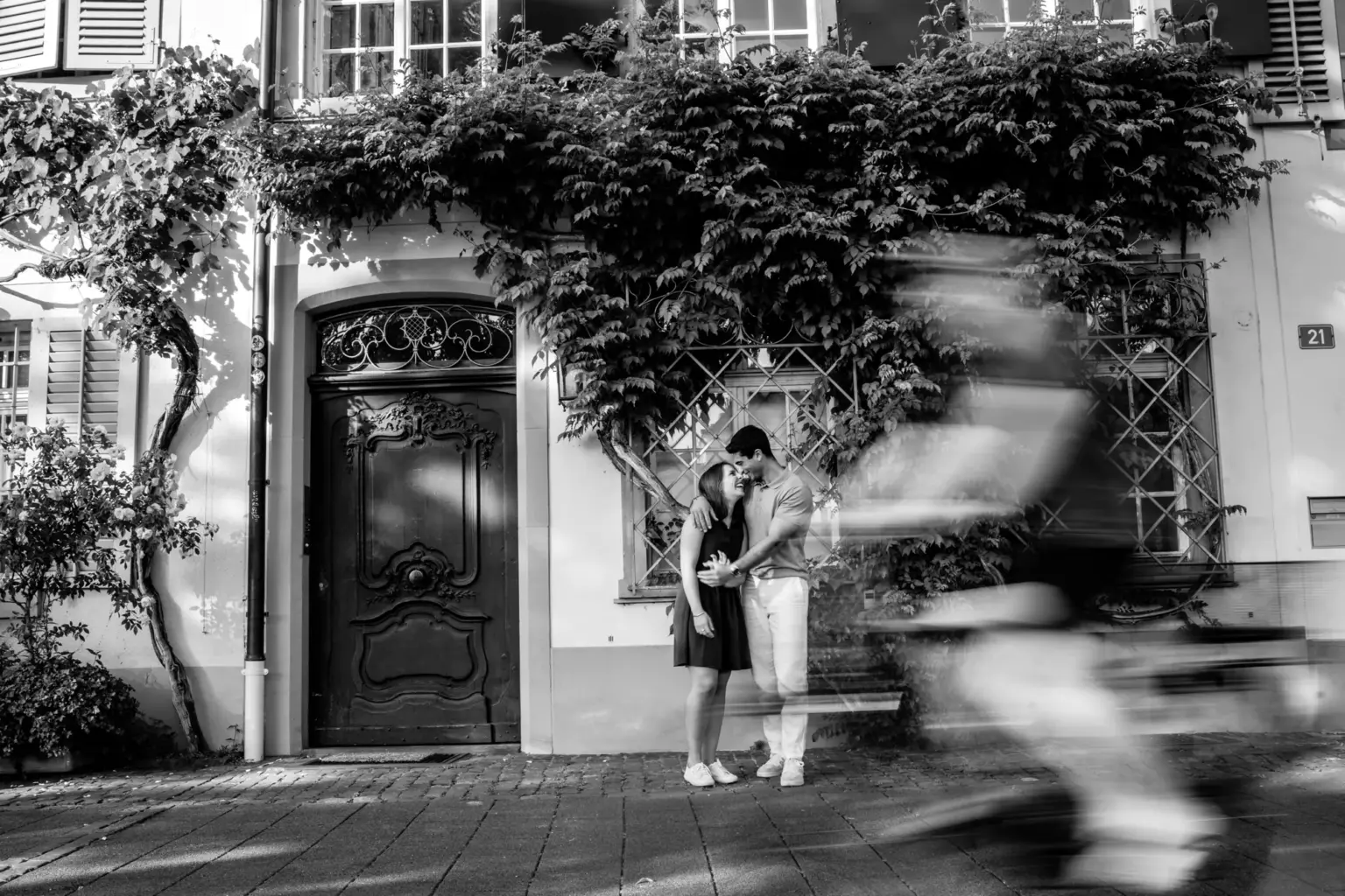 Paar vor einer bewachsenen Altstadttür während ein Radfahrer vorbeifährt